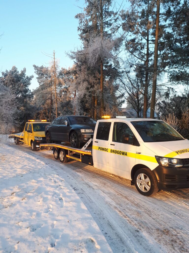 Samochód na poboczu drogi z przybyłą pomocą drogową Hannover w tle, świadczącą usługi holowania i naprawy na miejscu.